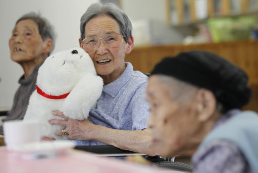 Image of a woman holding Paro, a caregiving robot