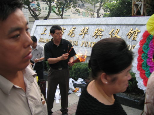 Image of a man burning joss paper as part of chinese funeral traditions