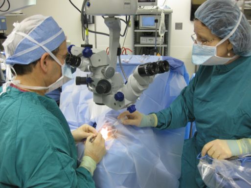 A doctor looking through a microscope doing minimally invasive surgery