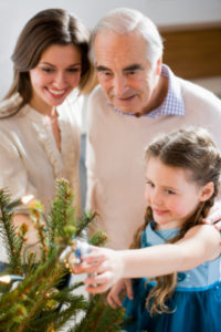 Elderly man decorating Christmas tree with daughter and granddaughter might benefit from a neck scan to predict dementia