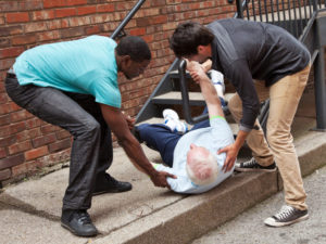 Two younger men assisting an older man after a fall.