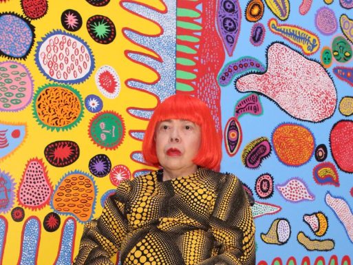 A photo of Kusama, creator of Infinity Rooms, standing in front of her work