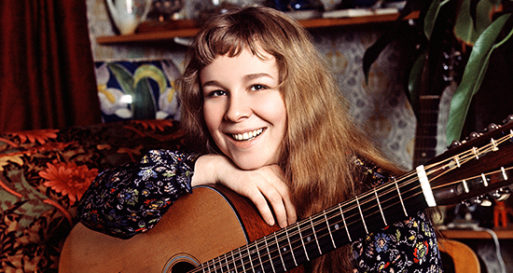 Sandy Denny resting her chin on top of her hand on top of a guitar.