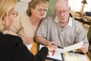 Elderly couple signing a power of attorney document with a fiduciary