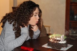 Photo of a girl blowing out candles on a cake.