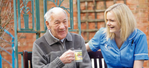 Man with forgetfulness talks to caregiver while drinking tea outside