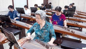 Elderly students in China learning to play traditional Chinese string instrument.
