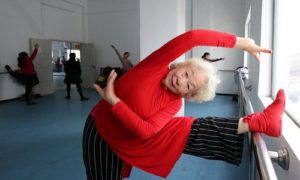 Elderly woman stretching and practicing a dance.