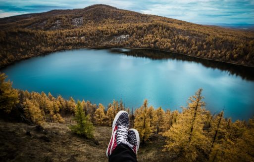 View of a person's shoes sitting above a lake.