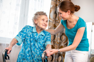 Young caregiver helping an elderly relative use a walker may be eligible for a tax credit