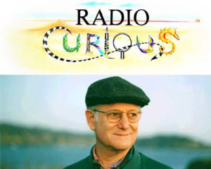 Barry Vogel standing under the logo for his Radio Curious radio show.