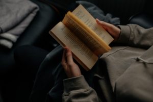 A person holding an open copy of "Intoxicated by My Illness" in his lap 