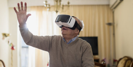 Senior man raising his hand while using a virtual reality headset.