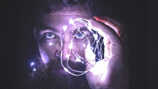 A man examines a light-filled structure that resembles a brain, recalling the scientific study of near-death experiences.