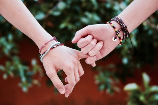 Two young LGBTQs holding hands shows empathy lessens risk of suicide