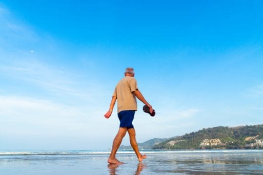 Man with positive attitude about aging walking on beach