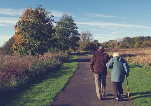 an older couple walk together down a path still in love