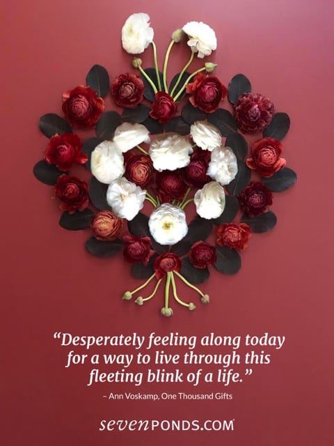 Handmade heart of flowers on a red background with a quote about loss
