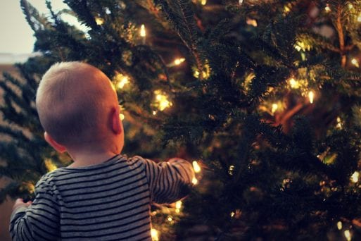Baby touching Christmas tree while grandparents baby sit