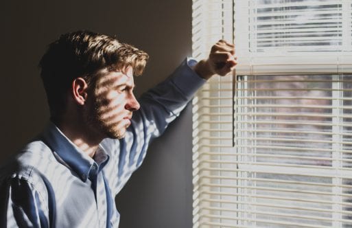 Image of man staring out the window experiencing grief at the workplace