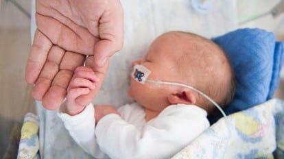 preterm infant holding hand of adult