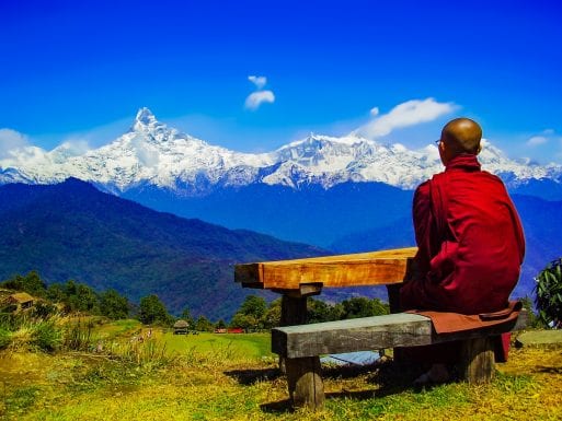 A monk views the Himalayas fro a picnic table.