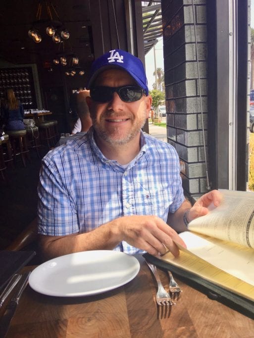 John Lilley at a restaurant wearing a Los Angeles Dodgers baseball cap.