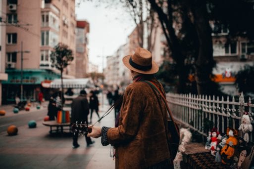 A man plays guitar on the street, boosting the mental health of others.