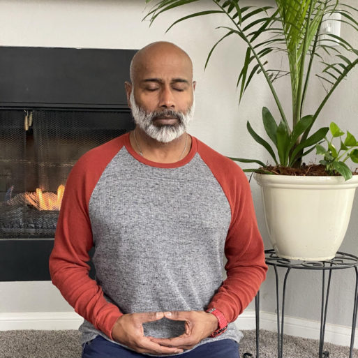 Les Aria, PhD, meditating in his home in front of a fireplace. Mr. Aria teaches patients to manage pain with mindfulness and meditation