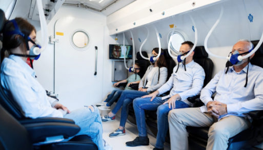 Hyperbaric oxygen treatments may help reverse aging; four people in room with medical oxygen masks on receiving hyperbaric oxygen treatment