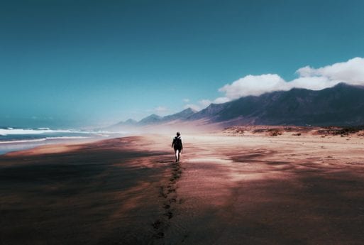 A human figure walks along a beach, evoking Nome Emeka Patrick's poem.