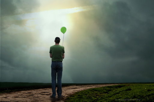 A man holding a balloon in a ray of sunlight, representing a near death experience