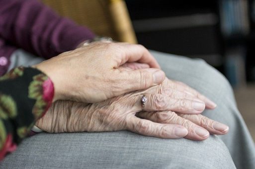Hand on top of elderly hands in lap - vaccines for family caregivers