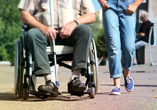 A person in a wheelchair, with a young person walking alongside, depicts how beliefs influence the experience of old age.