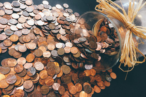 Jar of pennies spilled on black surface - crowdfunding funerals