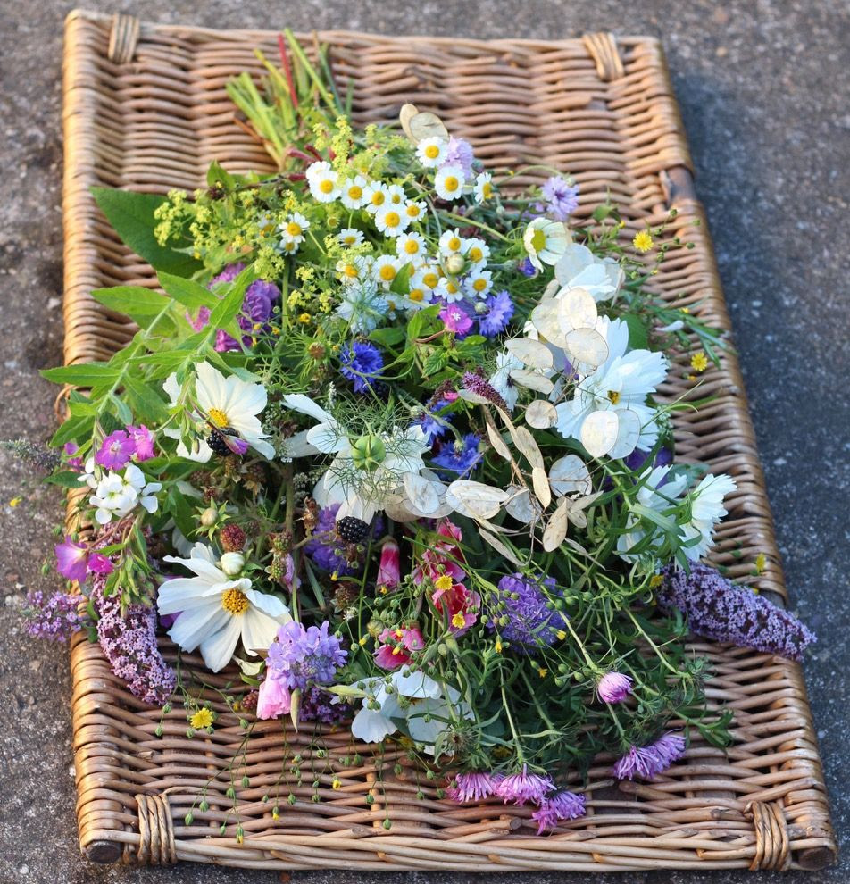 A wildflower casket spray laid out on a straw mat.