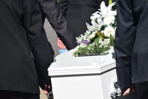 hands carrying coffin of covid-19 victim at funeral