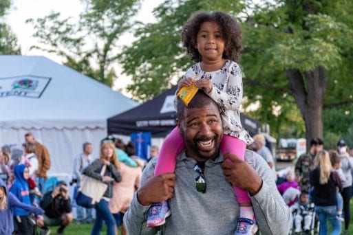 A father laughingly holds his daugher on his shoulders, before she will one day carry him as outlined in the poem by Marjorie Saiser.