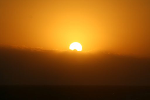 A sun sets in an orange sky during a heatwave, which can cause heat-related deaths..