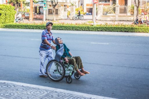 A young man pushes an elderly woman down the street to avoid heat-related deaths..