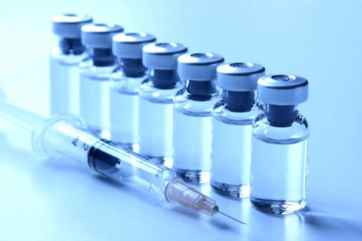 Photograph of vaccine bottles lined up next to syringe - vaccine boosters