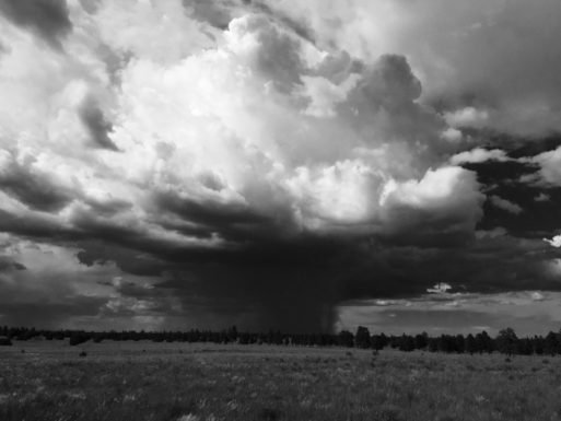 Black and white photograph of cloudy sky over desert landscape - elyas alavi