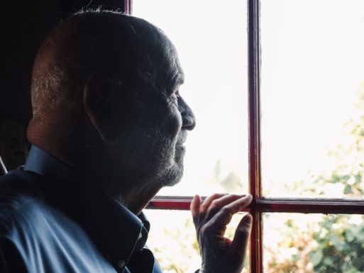 A man with dementia, who may face early death as well as debilitating illness, looks out a window.