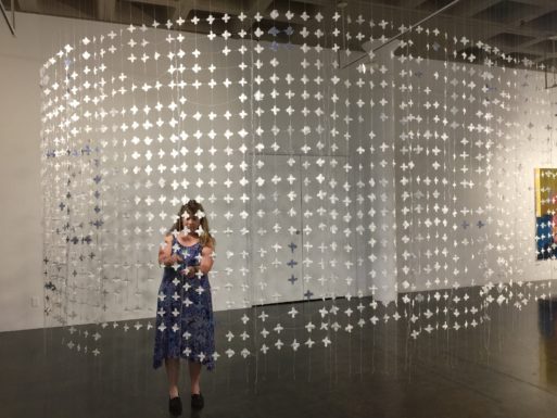 Ingrid Tegner working on an installation of star shapes hanging in strings from the ceiling.