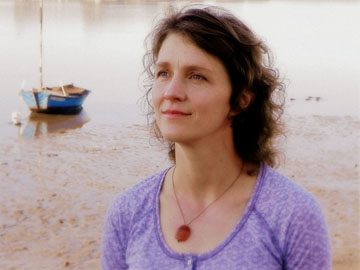 Poet Lisa Coffman stands near a lake.