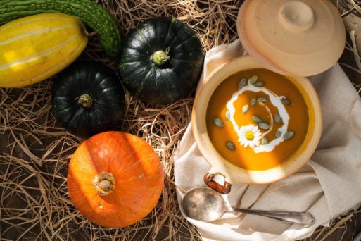 A bowl of soup sits amid colorful fall squashes in this display of both loss and plenty.