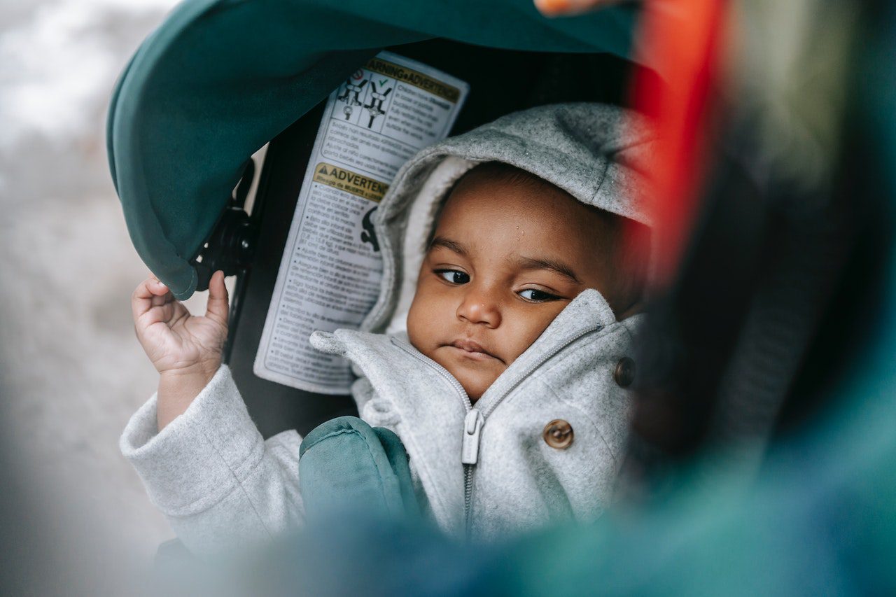 A child orphan who lost a parent to COVID-19 gazes out from a carrier.
