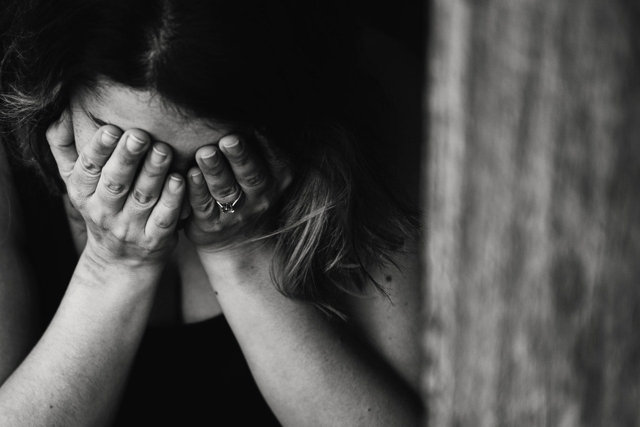 A woman experiencing prolonged grief holds her face in her hands.
