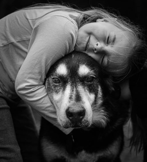 a little girl hugs her dog in an end-of-life-pet photograph