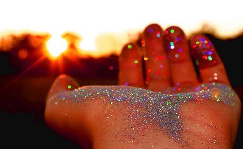 A hand holding sparkles mixed with cremation ashes 